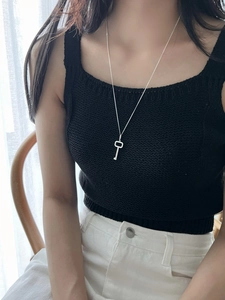 Detail view of a 925 sterling silver key pendant necklace worn on a black knit top