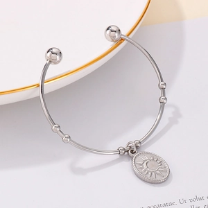 Détail du bracelet jonc en acier argenté avec pendentif pièce soleil et lune
