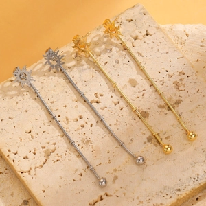 Detail of gold and silver sun tassel earrings with metal beads on a natural stone surface
