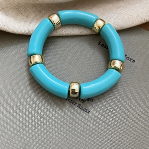 Close-up of turquoise acrylic segments and gold metal beads on a minimalist bracelet
