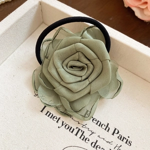 Detail eines graugrünen Stoffblumen-Haargummis mit mehrlagigen Chiffon-Rosenblättern