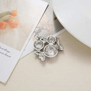 Christmas silver three-candy brooch with pin detail and polished metal backing