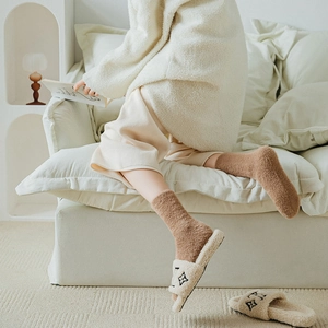 Close-up of fluffy brown mink velvet socks paired with cozy white floral pattern slippers