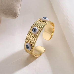 Detailansicht eines 18K vergoldeten breiten Armreifs mit bösem Blick und Hammerschlag-Textur