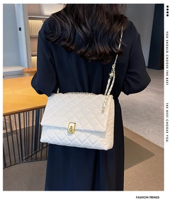 Rear view of a model wearing a white quilted crossbody bag with gold chain strap