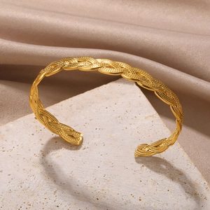 Detailed view of golden twisted braid texture on an open cuff bracelet for women