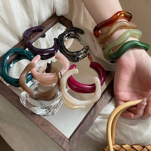 Close-up of irregular wave resin bangles with marble texture displayed on a mirror