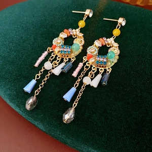 Détail de boucles d'oreilles bohèmes avec cristaux colorés, perles et glands sur velours