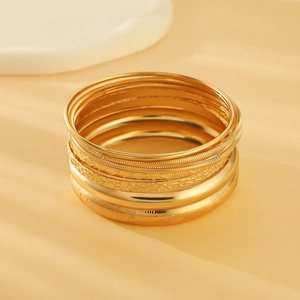 Detail showing various textures of gold alloy bangles with polished and engraved finishes