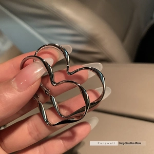 Macro shot of silver heart earrings with twisted streamlined design and glossy finish