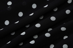 Detail shot of black chiffon fabric featuring white polka dot print texture