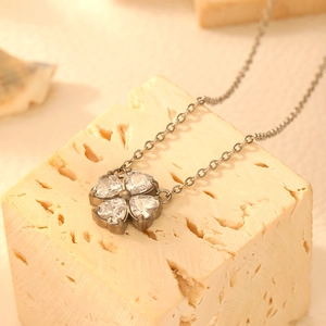 Elegant silver titanium clover necklace featuring heart-shaped clear zircons in warm light