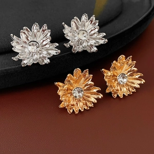Macro detail of gold and silver flower stud earrings with sparkling zircon centers