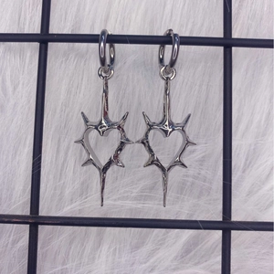Silver hollow thorn heart earrings with punk style hoop dangles on fur background