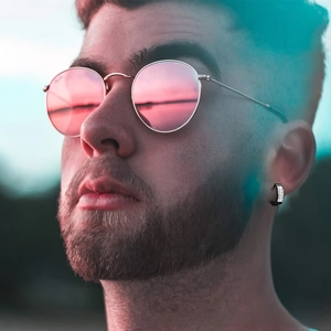 Macro shot of men's black huggie earring with embedded crystals and pink sunglasses