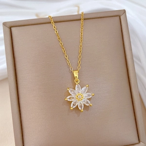 Close-up of golden floral bud pendant with white crystals on beige jewelry box