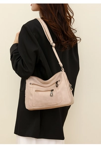 Detail of soft beige faux leather crossbody bag with multiple metal zipper pockets