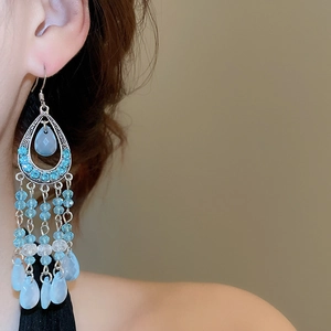 Detail of vintage bohemian drop earrings with blue tassels and silver metal accents