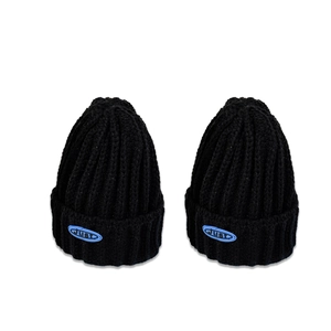 Deux bonnets en tricot côtelé noir avec étiquettes bleues sur fond blanc uni