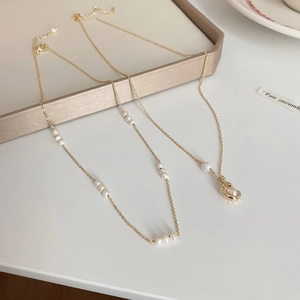 Vintage butterfly pearl necklace with gold chain displayed on champagne jewelry box