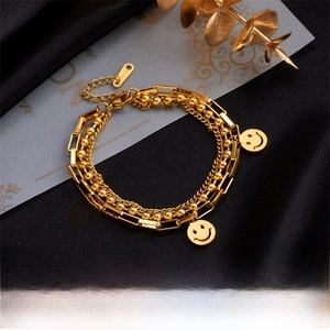Macro detail of triple-layer gold titanium steel bracelet featuring smile face charms