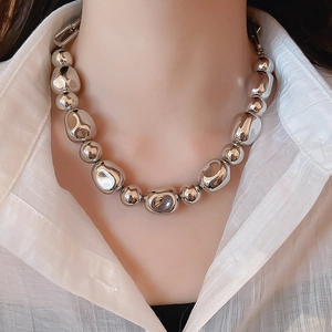 Gros plan d'un collier à grosses perles argentées avec sphères métalliques irrégulières