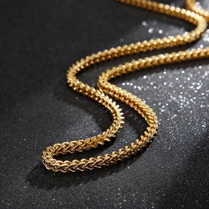 Polished golden stainless steel link chain necklace for men with woven texture on black background