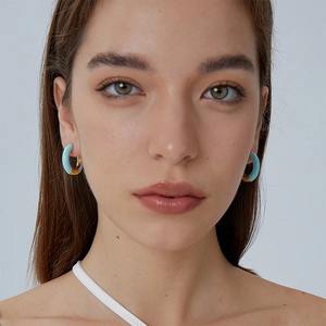 Minimalist C-shaped enamel gold earrings in sky blue shown on a model for luxury style