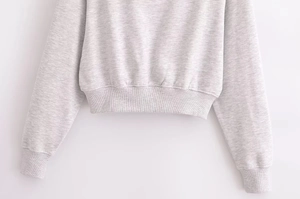 Detail of ribbed hem and cuffs on a cropped light gray cotton tracksuit set for women