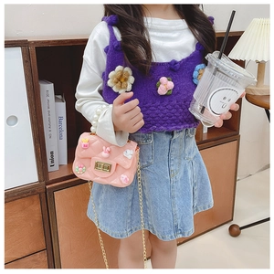 Pink silicone kid handbag with pearl handle and cartoon charms shown with a young model