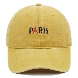Macro detail of embroidered Paris logo and Eiffel Tower on yellow washed baseball cap