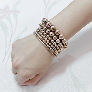 Rose gold stainless steel beaded stretch bracelets layered on wrist with metallic shine