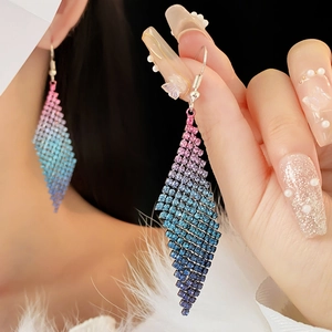 Vue macro de boucles d'oreilles losange en strass dégradé portées par un modèle