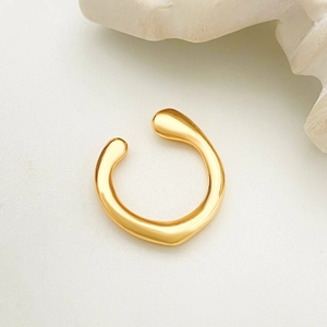 Dettaglio macro di un earcuff lava dorato irregolare con design organico e lucido