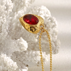Macro shot of 18K gold plated heart pendant with red gemstone on white coral