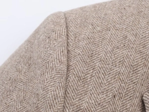 Macro shot of brown herringbone tweed fabric texture on a wool blazer shoulder