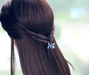 Dettaglio del fermaglio per capelli a farfalla in smalto blu con strass su capelli castani