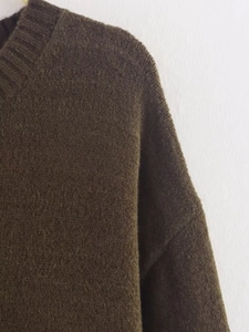 Detail of dark brown knit sweater featuring drop shoulders and thick textured fabric