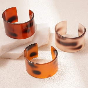 Three wide acetate resin open bangles with tortoiseshell patterns in diverse colors