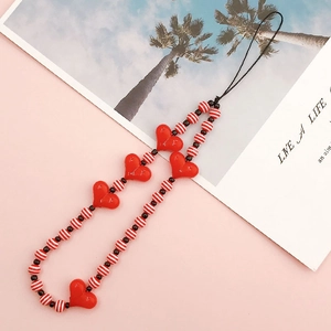 Detail of red heart beads and striped round beads on a handmade phone strap charm