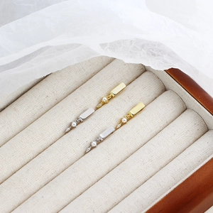 Detailed view of gold and silver rectangle earrings with pearls and crystals on velvet