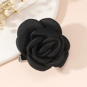 Detail shot of a black satin fabric rose brooch on a decorative white ceramic tray