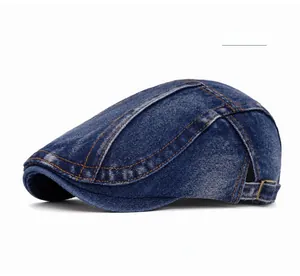 Detail of dark blue denim beret featuring orange stitching and metal buckle strap