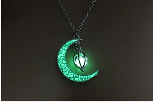 Detailed close-up of a glowing moon pendant necklace featuring a luminous green bead