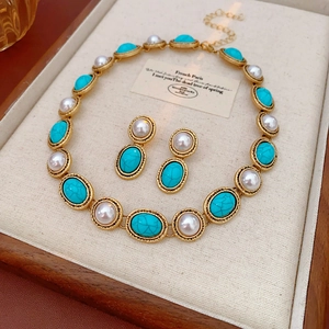 Detail of vintage jewelry set featuring turquoise gems and pearls in gold settings
