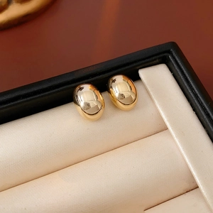 Detailed macro shot of gold oval stud earrings resting in a premium black jewelry display box