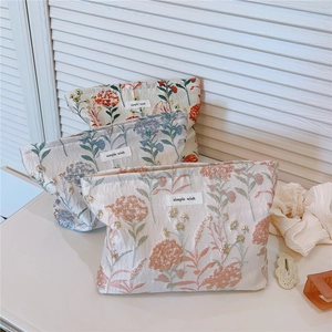 Close-up of elegant floral embroidery and gold thread details on the makeup bag