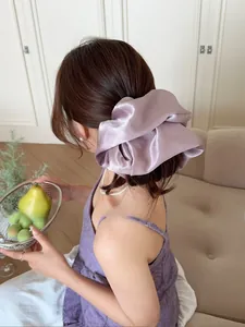 Detailed view of large purple satin scrunchie showing glossy texture and rich pleats