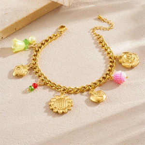 Bracelet à breloques plaqué or avec pendentifs fruits et fleurs sur fond de pierre beige