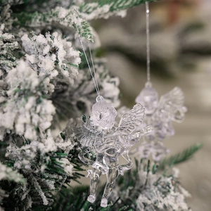 Macro shot of transparent acrylic angel ornament with silver cord on snowy Christmas tree